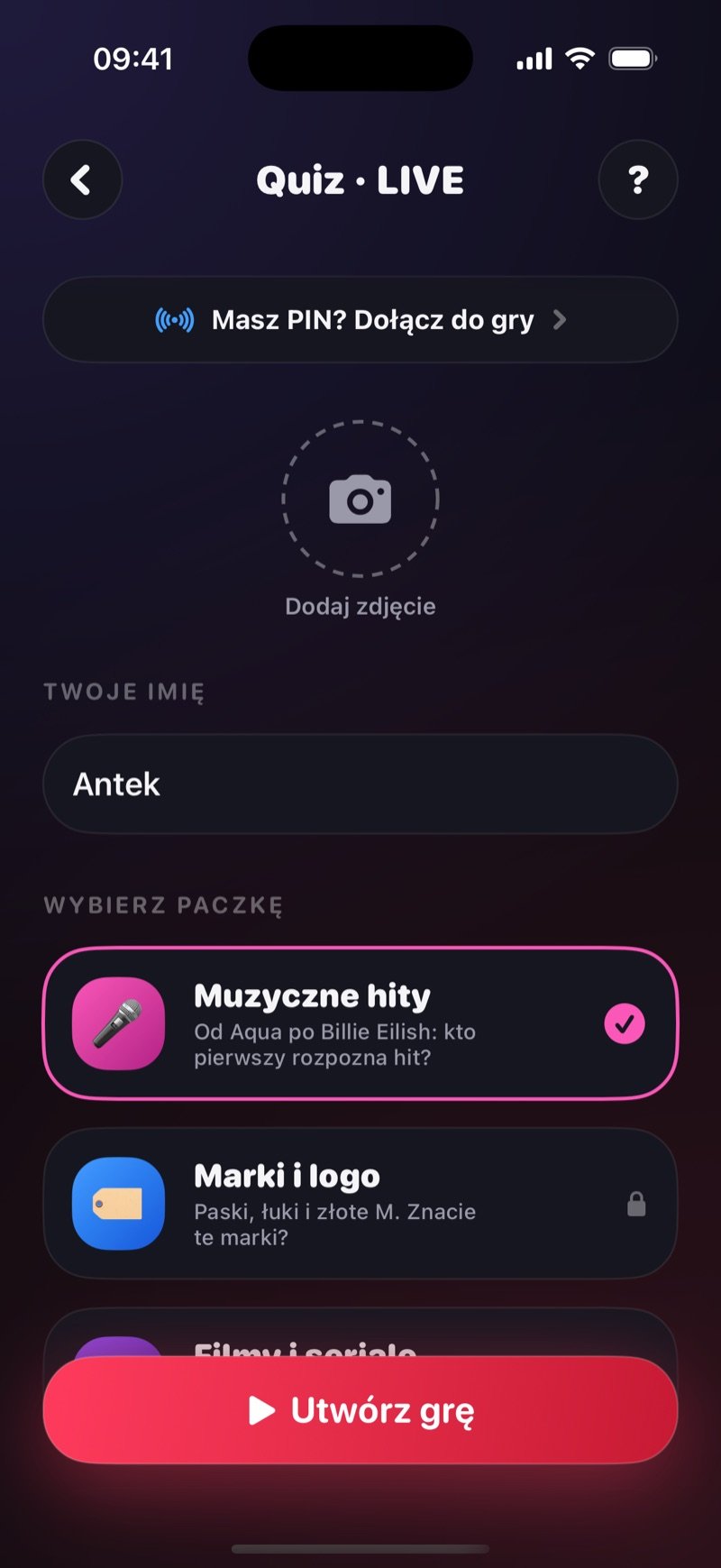 Ekran tworzenia gry w Quiz LIVE w Dronk: wiersz Got a game pin? Join the game, kółko Add photo, Your name ustawione na Jacob, Pick a pack z zaznaczonym Music Hits i Brands & Logos z kłódką oraz przycisk Create game (zrzut z wersji angielskiej)