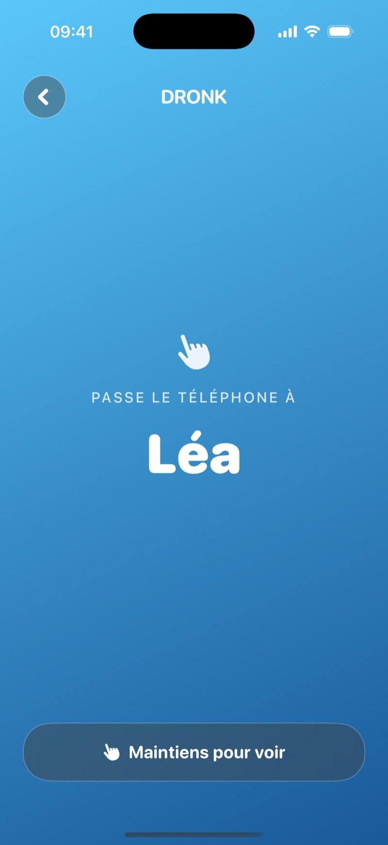 L'écran de passage du téléphone de l'Espion sur un dégradé bleu : Pass the phone to Olivia, avec un bouton Hold to reveal et la carte encore cachée (capture de la version anglaise)