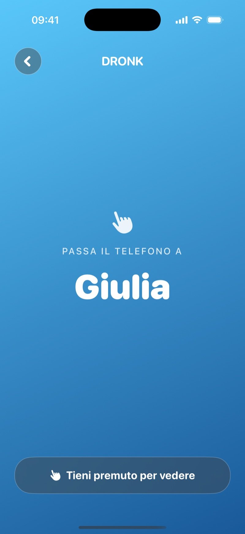Schermata passa-il-telefono di La Spia su sfondo blu sfumato: Pass the phone to Olivia, con un pulsante Hold to reveal e la carta ancora coperta (screenshot della versione inglese)